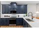 Modern kitchen featuring navy cabinets, stainless steel appliances, and white quartz countertops at 9980 Red Canoe Aly, Orlando, FL 32832