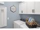 Laundry room with white appliances, blue walls, overhead cabinets, and a decorative laundry sign at 9980 Red Canoe Aly, Orlando, FL 32832