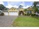 Charming yellow home with a three-car garage, lush lawn and brick driveway at 1006 Hanging Vine Pt, Longwood, FL 32750