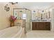 Bathroom featuring a soaking tub, a double sink vanity, a separate glass shower, and tile flooring at 12137 Buttonbush Loop, Leesburg, FL 34788