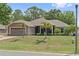 Beautiful one-story house with a well-kept lawn, palm trees, and a two-car garage at 12137 Buttonbush Loop, Leesburg, FL 34788