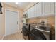 Functional laundry room with modern washer and dryer, white cabinets, and tile flooring at 12137 Buttonbush Loop, Leesburg, FL 34788