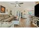 Open-concept living room with wood floors, a large sectional sofa, and a view into the kitchen at 12137 Buttonbush Loop, Leesburg, FL 34788
