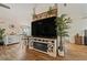 Spacious living room with wood floors, a large TV, and decorative shelving with plants at 12137 Buttonbush Loop, Leesburg, FL 34788