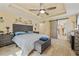 Serene main bedroom with tray ceilings, a ceiling fan, and an ensuite bath with a sliding barn door at 12137 Buttonbush Loop, Leesburg, FL 34788