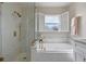 Modern bathroom with a glass-enclosed shower and a soaking tub with shuttered window at 2407 Oakington St, Winter Garden, FL 34787