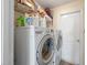 Functional laundry room featuring a washing machine, dryer, storage shelf, and a utility door at 2407 Oakington St, Winter Garden, FL 34787