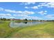 Scenic pond view surrounded by lush green grass and beautiful homes under a partly cloudy sky at 2407 Oakington St, Winter Garden, FL 34787