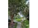 Lush backyard with a sidewalk leading to a tree-lined view of the community pond at 2516 Grassy Point Dr # 210, Lake Mary, FL 32746