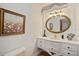 Charming bathroom vanity with an oval mirror and a decorative painting at 2828 Marquesas Ct, Windermere, FL 34786