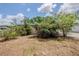 Shows the side view of a beige single-story home with a mix of greenery, under a blue sky with scattered clouds at 3025 Bon Air Dr, Orlando, FL 32818