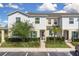 Charming townhome featuring a well-maintained lawn and landscaped front yard with trees and green shutters at 320 Primrose Dr, Davenport, FL 33837