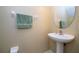 Neat half bathroom featuring a pedestal sink, round mirror, and a plush green towel at 3567 Shallot Dr # 103, Orlando, FL 32835