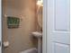 Well-lit half bathroom with a pedestal sink, round mirror, and fresh paint at 3567 Shallot Dr # 103, Orlando, FL 32835