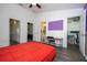 Bright bedroom features hardwood floors, ceiling fan, closet, workspace, and a striking red bedspread at 3567 Shallot Dr # 103, Orlando, FL 32835