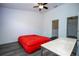 This bedroom features a ceiling fan, hardwood floors, workspace and a striking red bedspread at 3567 Shallot Dr # 103, Orlando, FL 32835