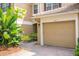 A view of the garage of a home with tropical plants and a brick driveway at 3567 Shallot Dr # 103, Orlando, FL 32835