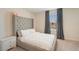 Bedroom featuring a bed with tufted headboard, neutral color palette, and natural light from the window at 4725 Coral Castle Dr, Kissimmee, FL 34746