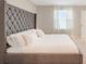 Bedroom featuring tufted headboard, neutral color palette, and natural light from the window at 4725 Coral Castle Dr, Kissimmee, FL 34746