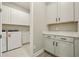 A laundry room with white cabinets above the washer and dryer, plus additional cabinetry with a sink at 5254 Citrus Leaf Blvd, Winter Garden, FL 34787