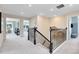 Bright hallway with black metal staircase railing and neutral decor leads to bedrooms at 6009 Tree Crossing Ln, St Cloud, FL 34771