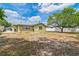 Backyard with the rear of the house, a mature shade tree, and a white privacy fence at 6042 Bolling Dr, Orlando, FL 32808