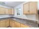 Compact kitchen with light wood cabinets, dark countertops, and a window view of a decorative stone wall at 6042 Bolling Dr, Orlando, FL 32808