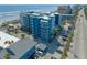 An aerial view of a blue apartment building next to the beach with parking, a pool, and neighborhood at 611 S Atlantic Ave # 4212, New Smyrna Beach, FL 32169