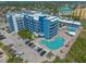 Aerial view of a blue apartment building with two pools, patios with lounge chairs, parking, and surrounding neighborhood at 611 S Atlantic Ave # 4212, New Smyrna Beach, FL 32169