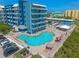 Aerial view of a bright blue apartment building next to a kidney-shaped pool with lounge chairs and umbrellas on the patio at 611 S Atlantic Ave # 4212, New Smyrna Beach, FL 32169