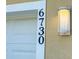 Close-up of the house number '6730' next to a modern outdoor light fixture at 6730 Orlando Drive, Indian Lake Estates, FL 33855