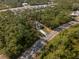 An aerial view of a residential area showcases a home surrounded by trees and well-maintained streets at 6730 Orlando Drive, Indian Lake Estates, FL 33855