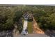 A stunning aerial view highlights a home on a tree-lined lot with an extra long driveway at 6730 Orlando Drive, Indian Lake Estates, FL 33855