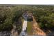 An aerial view of a home on a large lot features a long driveway, lush trees, and well-manicured grass at 6730 Orlando Drive, Indian Lake Estates, FL 33855