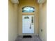 Inviting front entrance with a white door, arched transom window, and neutral stucco walls at 6730 Orlando Drive, Indian Lake Estates, FL 33855