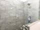 Walk-in shower with gray textured tiling and glass enclosure at 6730 Orlando Drive, Indian Lake Estates, FL 33855