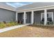 Inviting front entrance features a gray door, white pillars, and manicured landscaping at 72 Fairway Cir, Umatilla, FL 32784