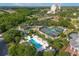 Aerial view featuring a pool, tennis courts, and lush landscaping near the main building at 7509 Mourning Dove Cir # 203, Reunion, FL 34747