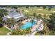 Aerial view of community pool, palm trees, lounge chairs, and nearby golf course under a bright blue sky at 7509 Mourning Dove Cir # 203, Reunion, FL 34747