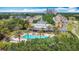 Aerial view of a community pool with palm trees, golf course, and surrounding neighborhood under a blue sky at 7509 Mourning Dove Cir # 203, Reunion, FL 34747