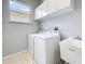 Bright laundry room featuring modern washer and dryer, utility sink, and overhead storage cabinets at 903 Kersfield Cir, Lake Mary, FL 32746