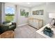 Cozy Bedroom with a wooden crib, green armchair, and a tranquil view from the window, perfect for relaxation at 9964 Red Canoe Aly, Orlando, FL 32832