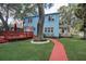 Charming blue two-story home featuring a red walkway, wooden deck, and lush green lawn at 1000 Pennsylvania Ave, Lakeland, FL 33803