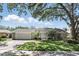 Charming single-story home with a lush green lawn, mature trees, and a two-car garage at 1129 Golfside Dr, Winter Park, FL 32792