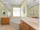 Spacious bathroom featuring a large soaking tub and dual vanities with wood cabinets at 12936 Freeman St, Windermere, FL 34786