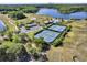 Aerial view of community pool, tennis courts, clubhouse, and parking lot, surrounded by lush greenery and a lake at 14315 Letham Grange Ct, Orlando, FL 32828