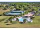 Aerial view of tennis courts and pool with clubhouse. Includes parking and lush landscape, near lake and golf at 14315 Letham Grange Ct, Orlando, FL 32828