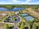 Aerial view of community tennis courts, pool, parking lot and clubhouse set amidst lush landscaping and a lake at 14315 Letham Grange Ct, Orlando, FL 32828