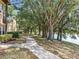 Paved walkway with scenic lake views, and mature trees along the water's edge at 163 Villa Di Este Ter # 105, Lake Mary, FL 32746