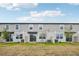 View of the back of townhomes with grassy yards, small trees, and blue sky above at 16466 Bird Of Paradise Ave, Clermont, FL 34714